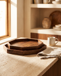 Two nested octagonal mango wood serving trays in walnut finish on a pale stone counter