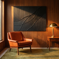 Large black palette-knife oil painting above a burnt orange leather lounge chair