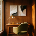 Two beige and black framed abstract prints above a teak desk