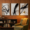 Three tan and beige brush stroke prints above a low walnut bookshelf